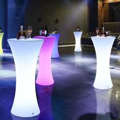 several lighted tables and stools with wine bottles on them