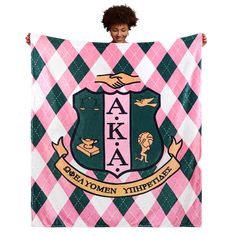 a woman holding up a pink and green blanket with the words aka on it