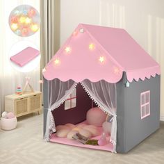 a pink and gray tent with lights on it's roof is in the middle of a child's room