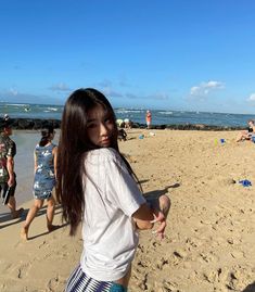 a young woman standing on top of a sandy beach