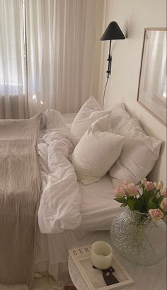 a white bed sitting next to a window in a room with curtains on the windowsill