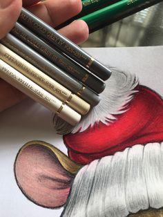 a hand holding several pencils in front of a drawing of santa claus's hat