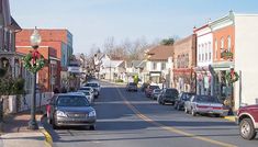 cars are parked on the street in front of buildings and wreathed trees, along with christmas decorations