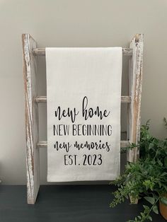 a wooden ladder with a white towel hanging from it's side next to a potted plant