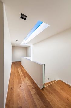 an empty room with wooden floors and skylights above it, is seen in this image