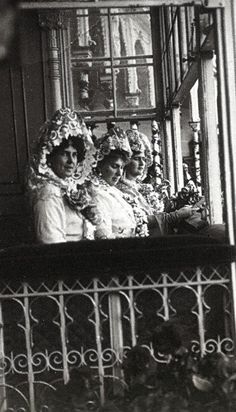 an old photo of three women dressed in fancy clothing on the balcony of a building