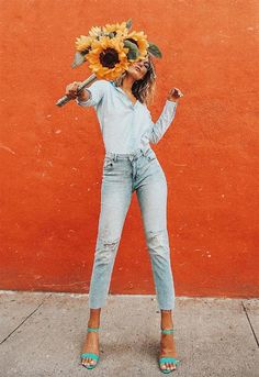 a woman holding a sunflower on her head and posing for a selfie with instagram