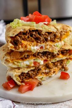 three quesadillas stacked on top of each other with tomatoes and lettuce