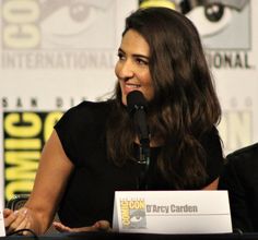 a woman sitting in front of a microphone at a press line for the 100th movie