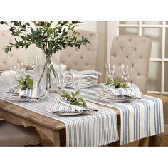 a dining room table set with place settings and flowers in a vase on the table