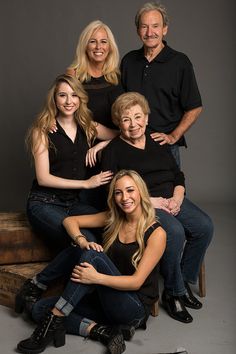 a group of people sitting on top of a wooden bench posing for a photo with their arms around each other