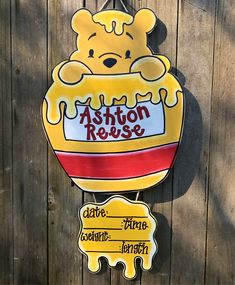 a winnie the pooh sign hanging on a wooden fence next to a wood wall