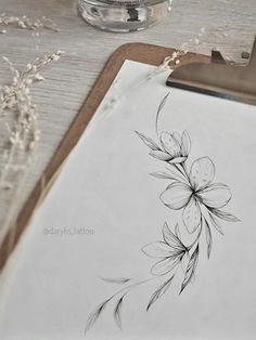 a piece of paper with some flowers drawn on it next to a pen and ink