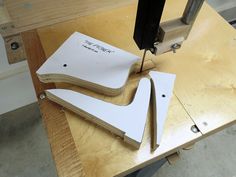 two pieces of wood sitting on top of a table with a sewing machine in the background