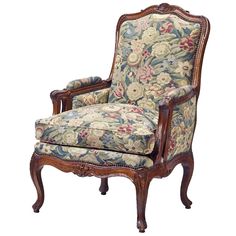 an ornate chair with floral upholstered fabric and wood frame, on white background