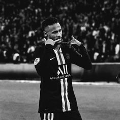 a black and white photo of a soccer player talking on the phone while holding his hand up to his ear