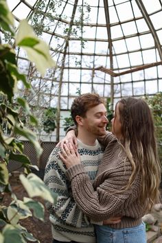 a man and woman embracing in a greenhouse