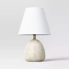 a white lamp sitting on top of a table next to a white light shade over it