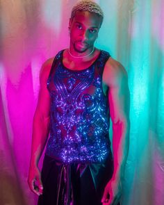 Introducing our men's sleeveless top, crafted from sheer black mesh fabric and adorned with intricate blue sequins. The sequins form elaborate, symmetrical patterns that cover most of the front, giving the top a sparkling and eye-catching appearance. Perfect for festivals, night outs, or any occasion where you want to stand out, this tank top combines edgy style with detailed craftsmanship. Add a touch of glamour and uniqueness to your wardrobe with this stunning piece. Sheer Tank Top For Party, Blue Stretch Tank Top For Party, Blue Sleeveless Top For Party Season, Blue Sleeveless Top For Festive Occasions, Sleeveless Blue Tops For Party Season, Festival Sequin Tops For Night Out, Fitted Blue Vest For Party, Sequin Tops For Night Out And Festivals, Sleeveless Blue Top For Festive Occasions