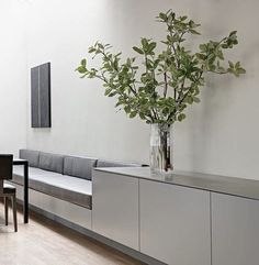 a dining room table with chairs and a plant in a vase on top of it