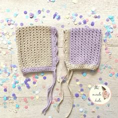 two crocheted mittens sitting on top of a wooden table next to confetti