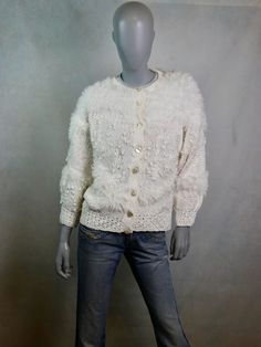 This plush white cardigan is a mixture of knit and crochet hand-craftsmanship and features eye-catching soft fuzzy threaded areas and small baubles. The elegant 1980s vintage sweater has a round neckline and closes in the front with eight glowing pearlescent buttons. Condition: Near Mint (Like New ... Professionally Cleaned ... soft and supple, with no stains, tears, wear spots, or weaknesses in the seams)  Size: XL, 16/18 US, 20/22 UK Bust = 48 inches (121.92cm) Shoulder Width = 17 inches (43.18cm) Waist = 44 inches(106.68cm) Hips = 40 inches (101.6cm) Sleeve Length = 20 inches (50.8cm) Cardigan Length = 24 inches (60.96cm) Material: Cotton, Acrylic White Vintage Knitted Cardigan, White Knit Cardigan, Vintage Pullover, Vintage Soft, Fuzzy Sweater, Vintage Sweater, White Cardigan, 80s Vintage, 1980s Vintage