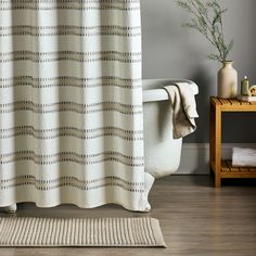 a bath tub sitting next to a white rug on top of a hard wood floor