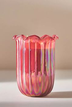 a pink glass vase sitting on top of a white table next to a brown wall