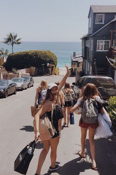 two women are walking down the street with their arms in the air and one is holding her hand up