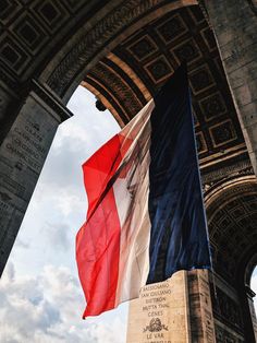 the flag is flying in front of an arch with writing on it that says france