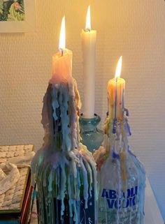 two bottles with candles in them sitting on a table