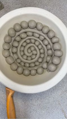 a white bowl filled with balls on top of a wooden spoon next to a tile floor