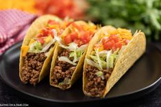 three tacos are sitting on a black plate