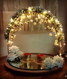 a table topped with candles and flowers on top of a wooden table next to a mirror