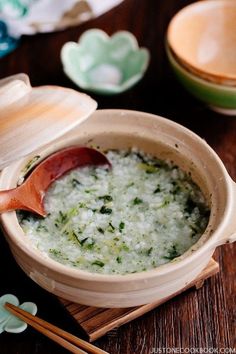 a wooden bowl filled with food next to chopsticks and bowls on a table