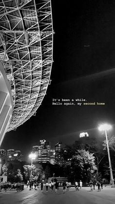 black and white photograph of people walking in front of a large structure with words written on it