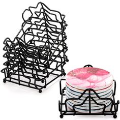 a stack of plates sitting on top of each other next to a black holder with a pink frosted donut