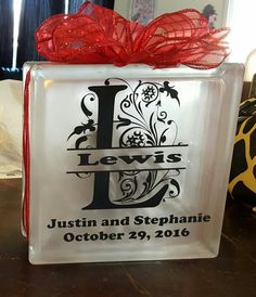 a glass block with the letter j on it and a red ribbon tied around it