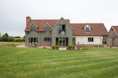 a large gray house sitting in the middle of a lush green field with lots of grass