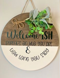 a welcome sign hanging on the wall next to a potted plant and some string