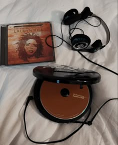 a cd and headphones laying on top of a white sheet with the cover pulled down