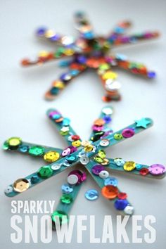 a snowflake made out of different colored buttons on a white surface with the words sparkly snowflakes written below it