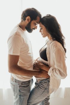 a man and woman standing next to each other with their hands on their stomachs