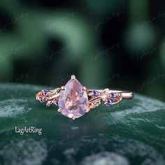 an engagement ring with a pink stone surrounded by amethorate and tan sapphires