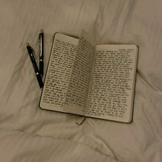 an open book with writing on it and a pen laying next to it in the bed