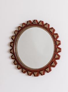 a round mirror hanging on the wall above it's reflection, with geometric shapes