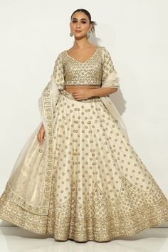 Ivory and gold kalidar lehenga with all over Padma bagh motif embroidery using zardozi highlights and tassel ornamentation. Paired with an elbow sleeves floral jaal embroidered leaf neck blouse with dangling glass beads hem and a bloom border embroidered dupatta. - Aza Fashions Raw Silk Embroidery, Embroidery Zardozi, Embroidered Leaf, Motif Embroidery, Embroidered Leaves, Embroidered Dupatta, Silk Embroidery, Elbow Sleeve, Bridal Lehenga