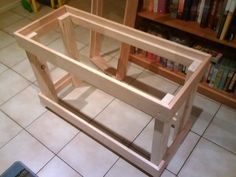 a wooden frame sitting on top of a tile floor next to a book shelf filled with books