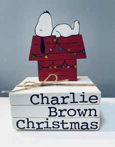 a wooden sign that says charlie brown christmas on top of two books with string and lights