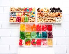 three plastic containers filled with different types of candies and nuts on a white tile floor